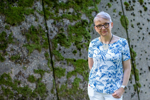 Clare Mason, Advanced Dementia Studies student, smiling in front of a wall of foliage on the University of Bradford campus.