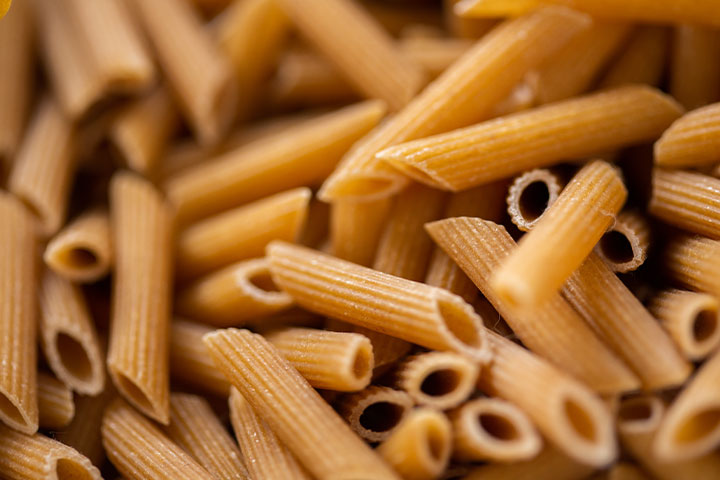 Dried penne pasta in a pile.