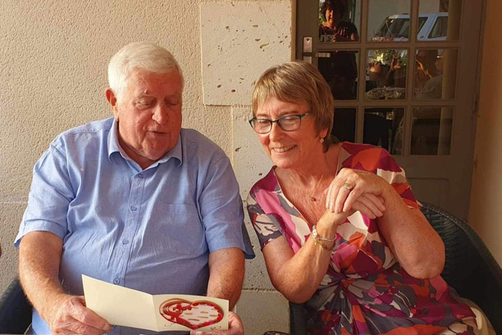 Two people sitting side by side looking at a card with a heart on the front