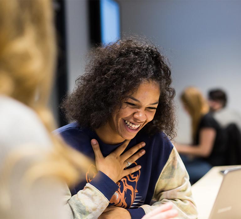 A student smiling looking at their computer