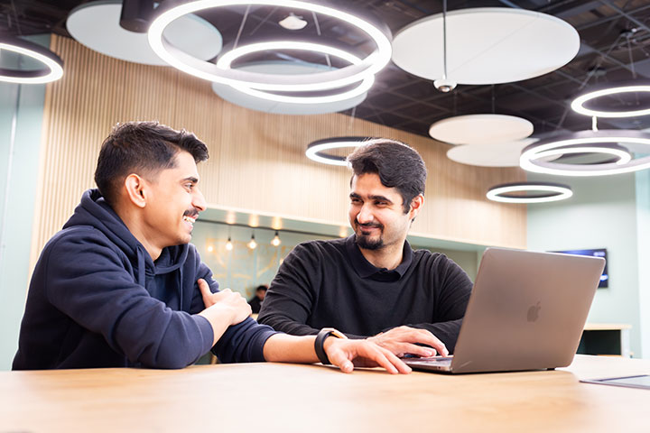 Two students sharing a laptop and smiling.