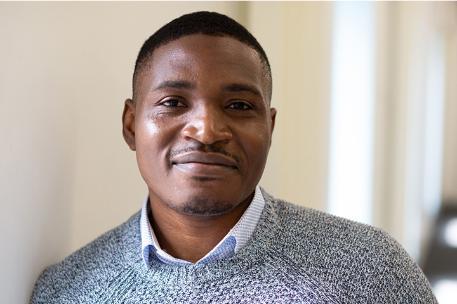 University student smartly dressed with grey jumper smiles at the camera