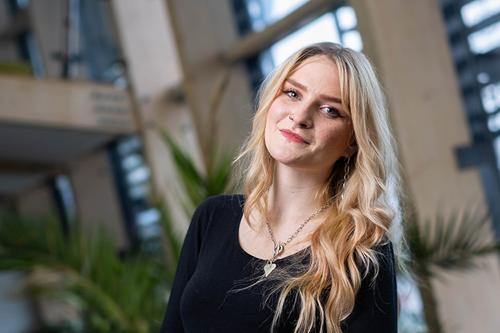 Molly, Public Health and Community Wellbeing student, smiling at the camera in a room in Bright Building.