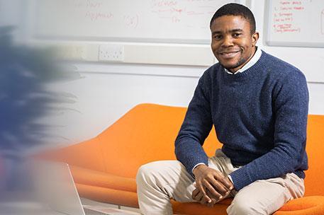 A postgraduate student sitting at a desk with their laptop.