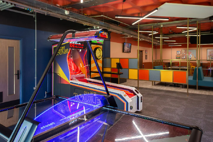 An empty gaming area with a pinball machine, darts and arcade game