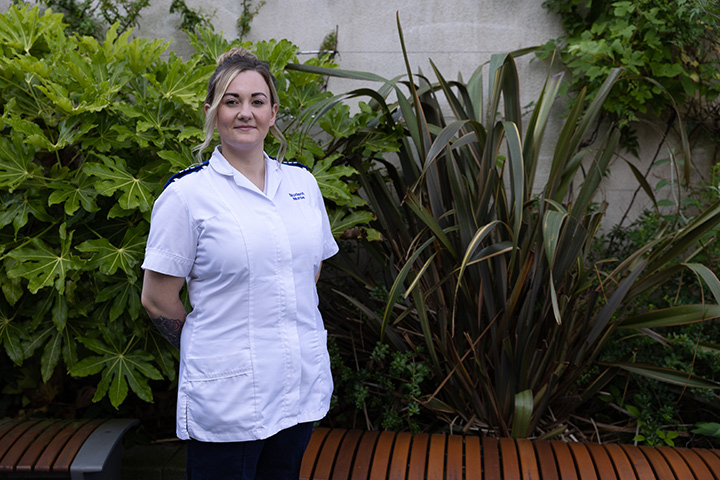 Child Nursing student, Demi-Jo Morgan, in uniform, stood in front of greenery.