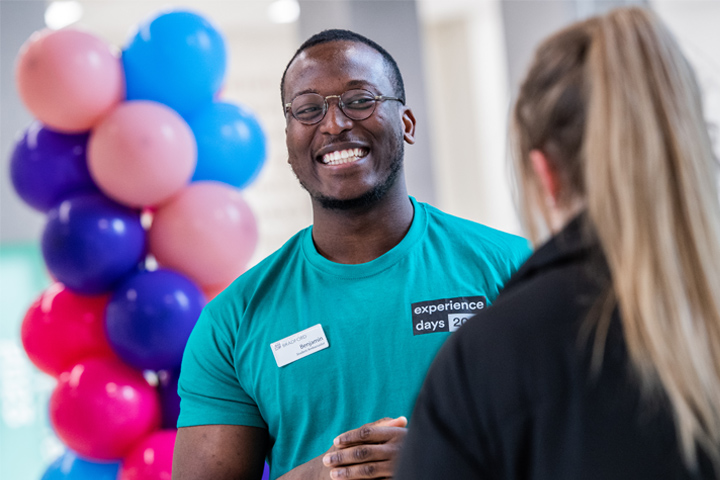 A student ambassador smiling whilst speaking to a prospective student