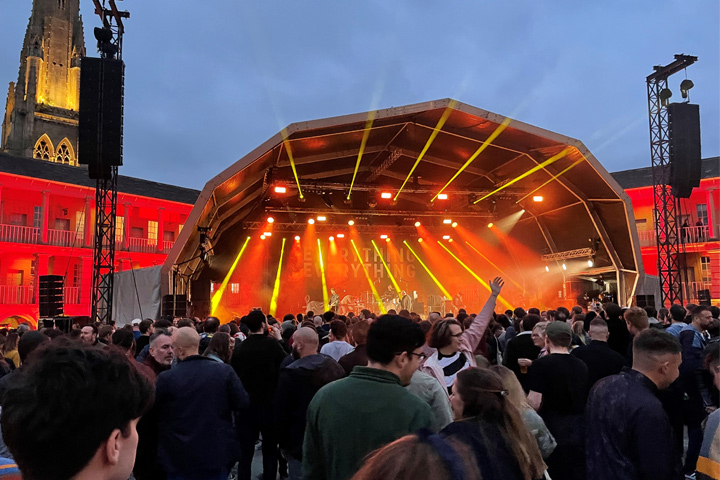 A concert stage lit up at night at The Piece Hall by Ryan Bennett