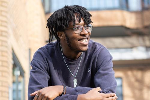 Student wearing glasses looking away from camera smiling