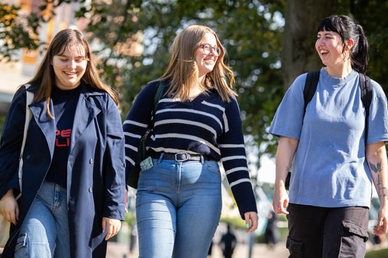 Three students walking together outside on campus at University of Bradford