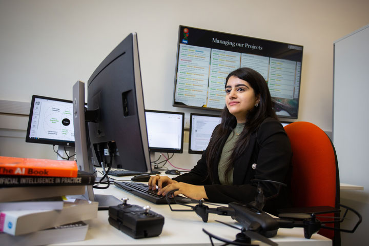 A person sitting at a desk typing on a computer keyboard and looking at computer monitor