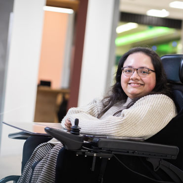 A student sitting in a wheelchair and smiling at the camera