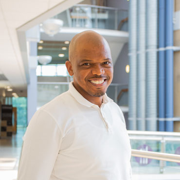 A student smiling at the camera and standing in Richmond Atrium at the University of Bradford