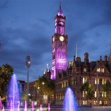 Bradford City square at night with the clocktower illuminated purple.