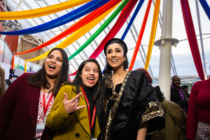 Anita Rani smiling and posing with two students at the Installation of the Chancellor event.