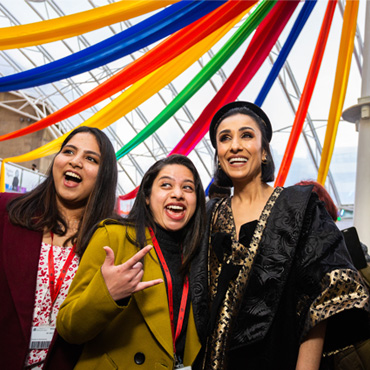 Anita Rani smiling and posing with two students at the Installation of the Chancellor event.