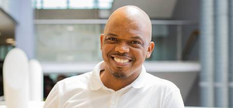 A student with a white shirt smiles at the camera.