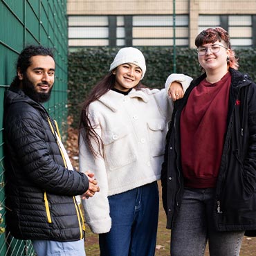 Three students smiling at the camera.