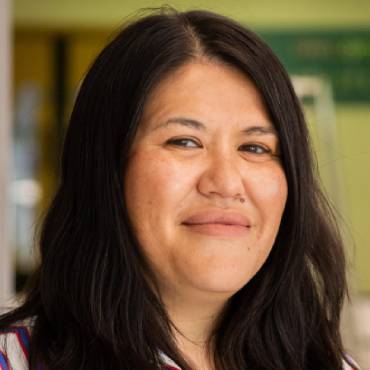 A student with long black hair smiles at the camera.