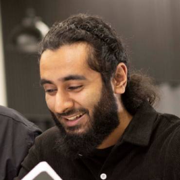 Two men smile while sat next to each other at a table