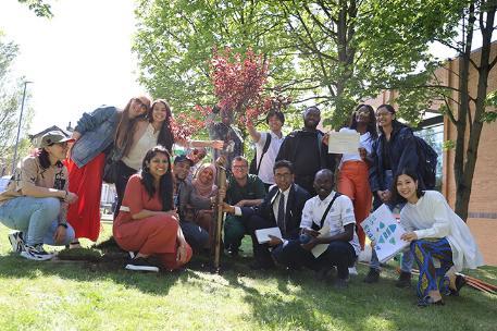 Students and staff posing after planting tree on campus