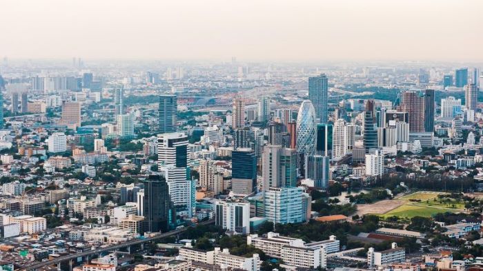 Bangkok skyline which includes multiple tall buildings, under a cloudy sky.