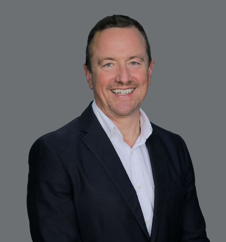 Alumnus David Jones (MBA) dressed in a suit and white shirt, in a formal setting.