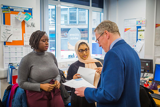 A small group of people discussing paperwork in an office.