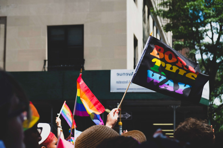 Crowd waving rainbow flags at an LGBT pride parade.