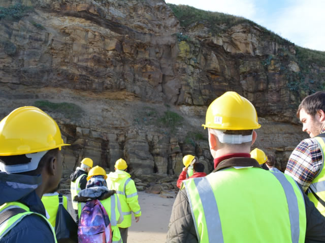 Students on a field trip looking up at a rock face.