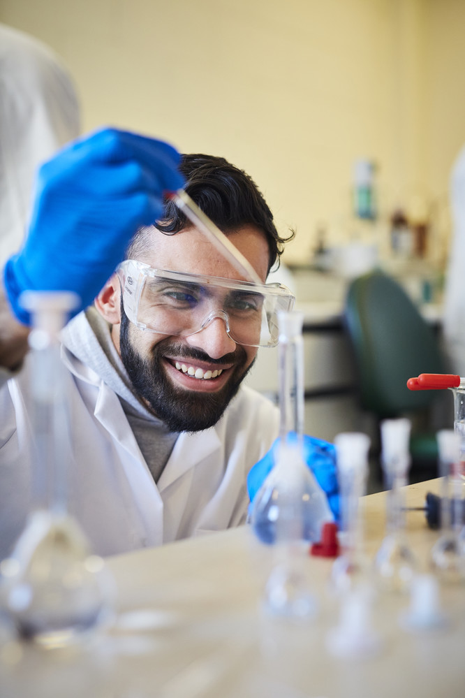 Student dropping a solution from a pipette into a vial.