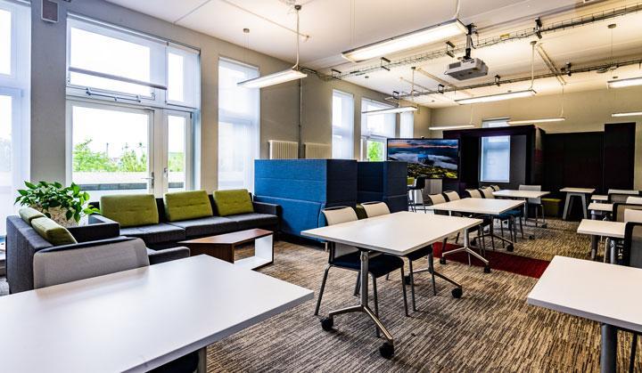 Photo of the Bright Building, Entrepreneurship Lounge showing meeting spaces including booths and desks