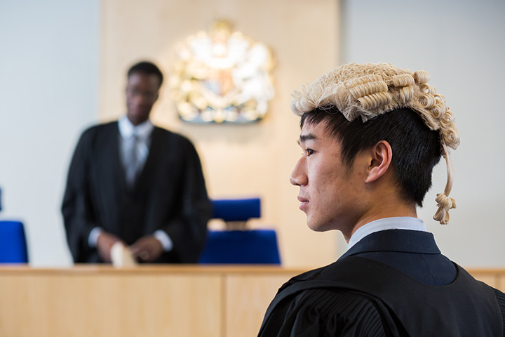 Students in wigs and tails conducting a mock criminal trial in the Lady Hale Courtroom on campus