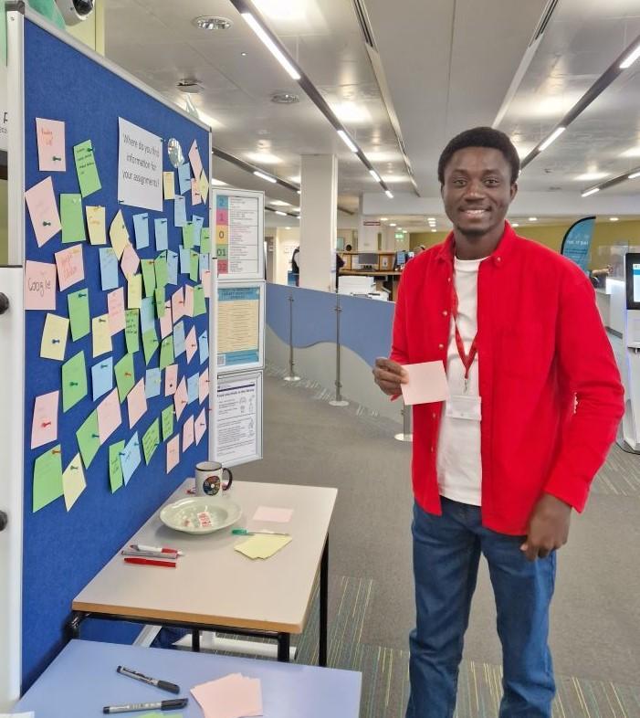 A student pinning post-it note to a board in the library