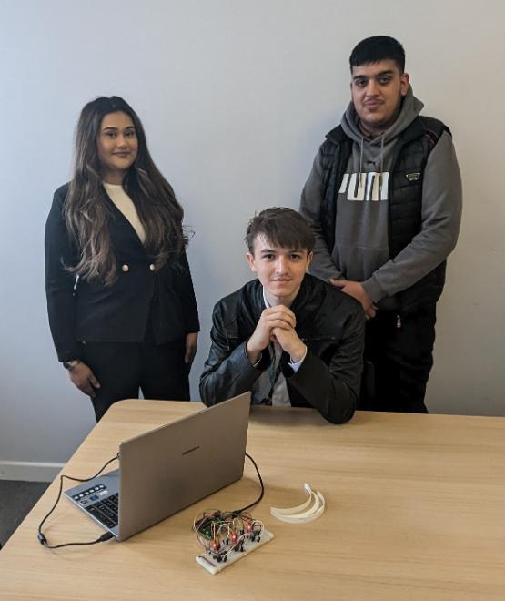 Three students at a desk with a laptop