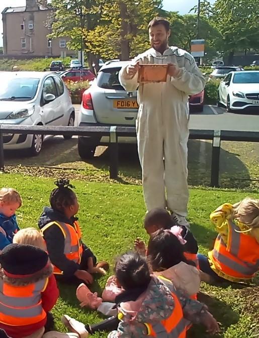 Beekeeper showing a nursery school child a bee frame