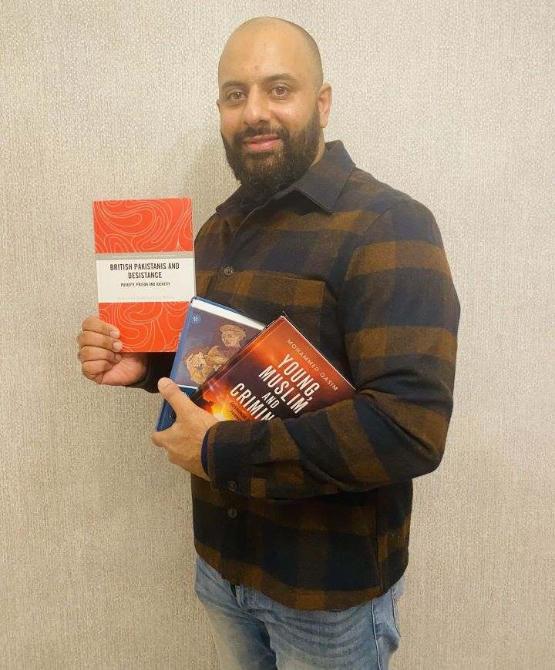 Staff member holds three book in their hands