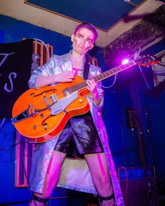 Person playing a guitar on stage during an entertainment show