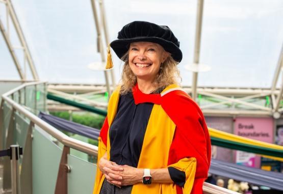 a person in graduation wear stands up for photo at university