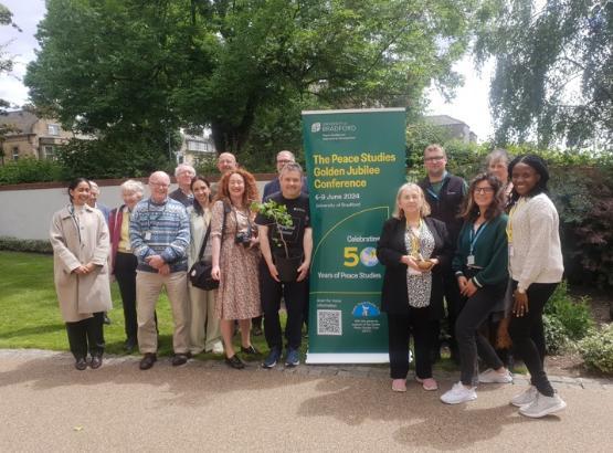 Group of people assembled around a ginkgo tree sapling