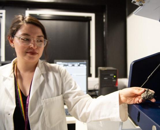 Dr Andrea Molina in the lab holding a sample of fools gold