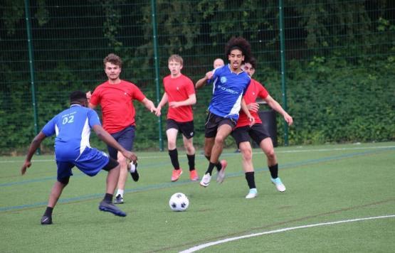 A photograph from a football match featuring a number of people going for the football