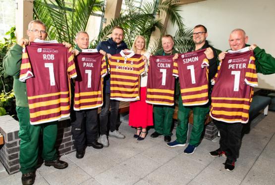 A group of people stood up holding football shirts