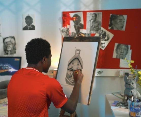 a person wearing a red T-shirt sat down drawing a picture