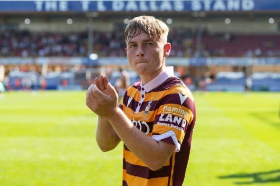 A football player dressed in kit on a pitch stood applauding