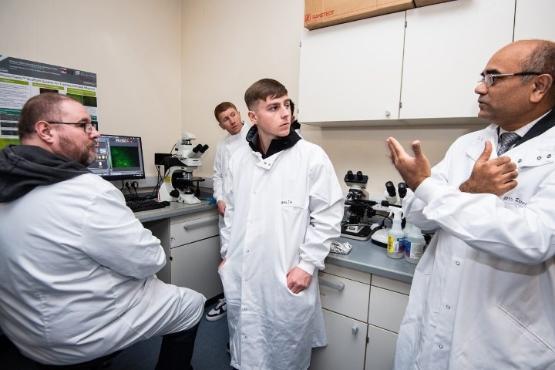 three people in science lab standing up wearing white coats