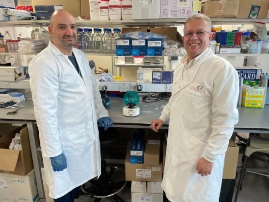 two staff members wearing white coats inside science lab