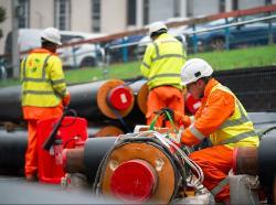 Workers lifting heat network pipes