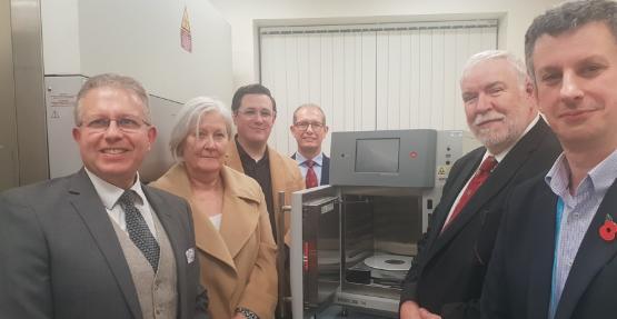 Academics and donors stood in front of a radiation source machine