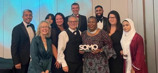 A group of university staff on stage at a ceremony celebrate after winning an award